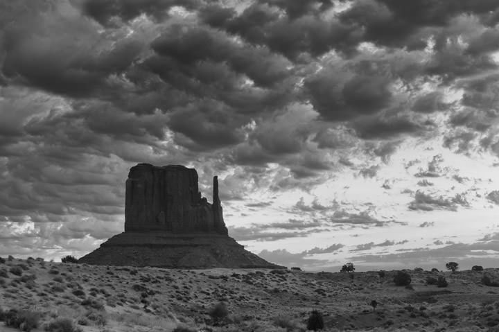 Monument Valley under a dramatic sky in black and white.